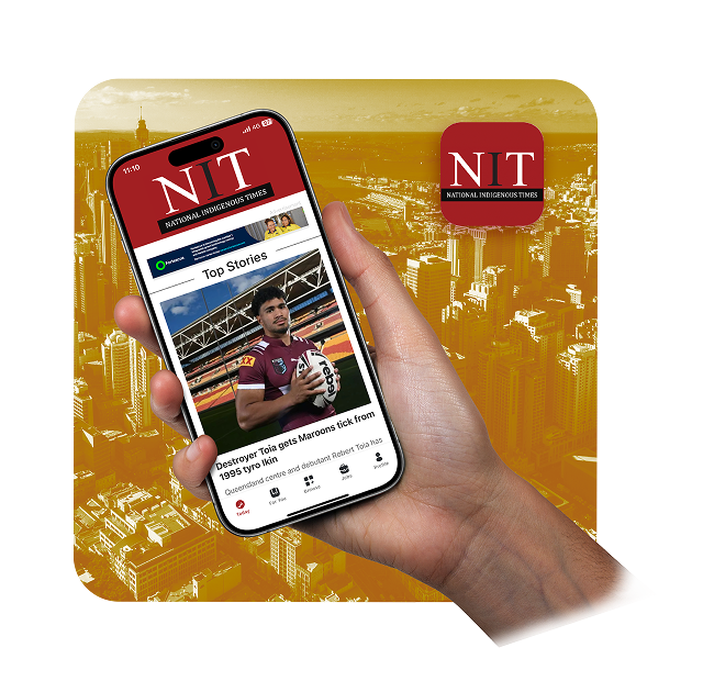 A hand holds a smartphone displaying the National Indigenous Times news app—created through expert app development—with a rugby player featured in the top story, set against a yellow-tinted cityscape and the NIT logo.