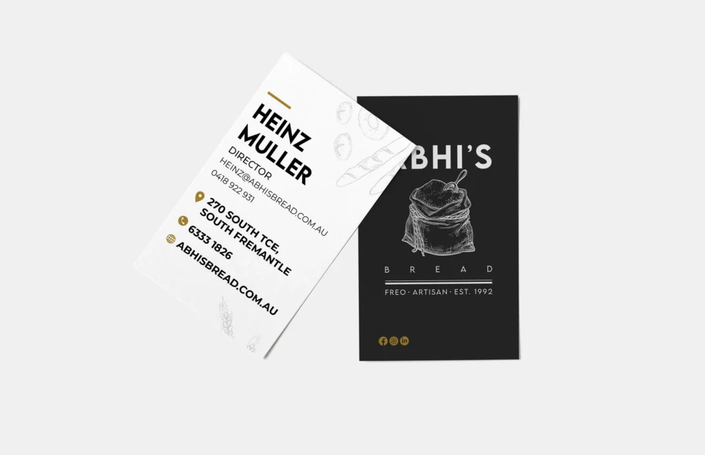 Two business cards on a white background: one is white with Heinz Muller’s contact details for Abhi’s Bread bakery; the other is black, featuring an illustration of bread and the Abhi’s Bread logo, tagline Fred – Artisan – Est. 1992.