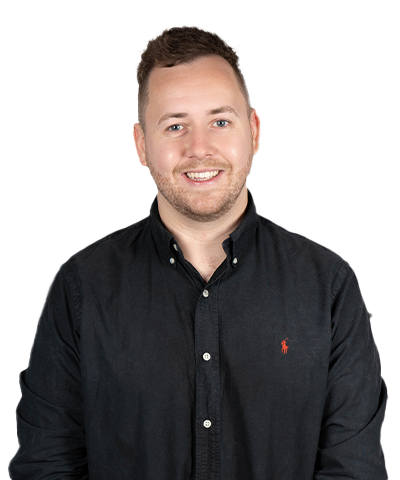 Scott Donovan, a smiling man with short brown hair and a trimmed beard, wears a black button-up shirt with a small red logo, standing against a plain light background.