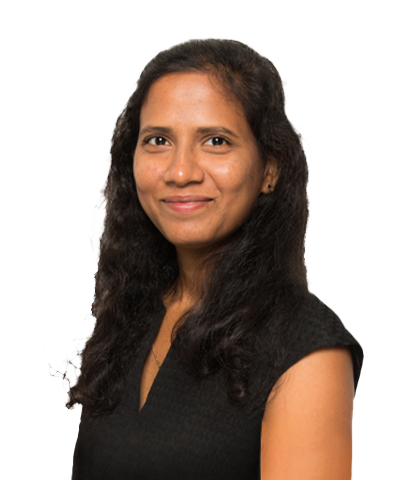 Nymisha Joginpally, with long, wavy dark hair and a medium skin tone, smiles at the camera. She is wearing a black sleeveless top and is posed against a plain white background.